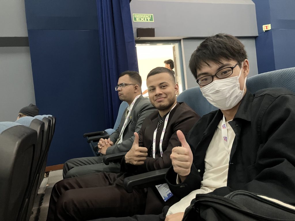 修士の千野と学会参加者が写っています。横並びの椅子に座っており、手前に千野、奥に他の参加者が並んでいる構図です。