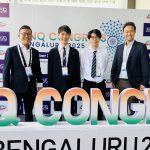 加藤研究室の集合写真です。 左から、博士課程の栗原さん、修士の千野・平野、一番右に加藤先生が立っています。中央下には両端が見切れている本学会のタイトルを模ったオブジェがあります。